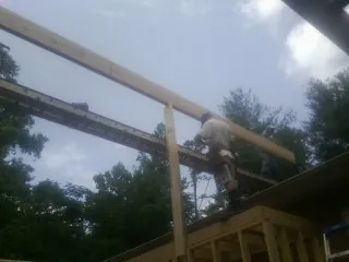 Carpenter setting a ridge beam over a new addition frame — Ice Dam Removal by Roofing Brothers in Bryantown