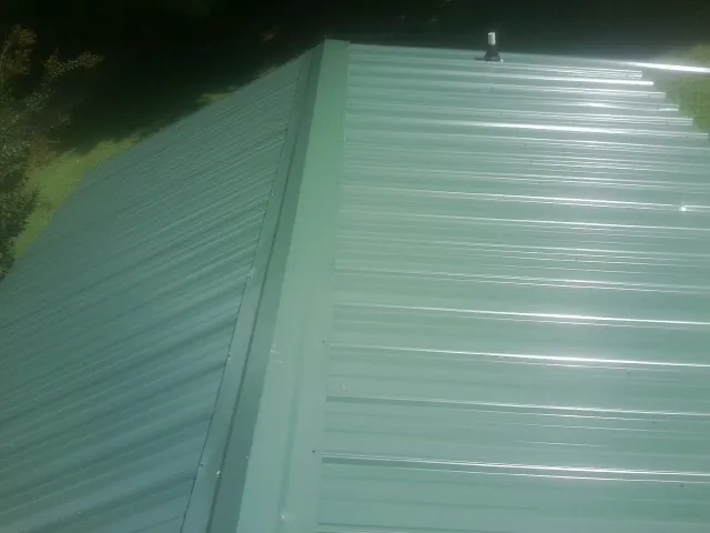 New green metal panels meeting at the ridge of a roof — Flat Roof Repair work by our crew in Bryantown