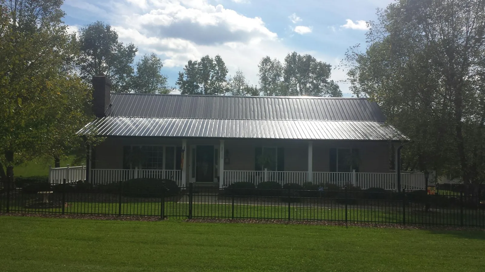 Gray metal roof on a brick ranch with a full width front porch — Gutter Guard Installation work by our crew in Bryantown