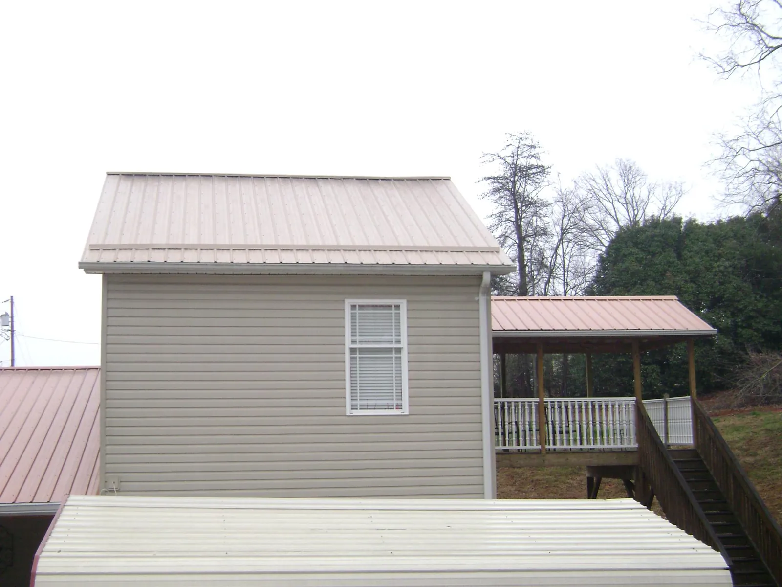 Tan metal roofs on a two story addition and attached porch, from a Roof Replacement job in Bryantown